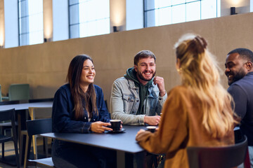 Friends Sharing Coffee and Laughter During a Casual Work Break at a Modern Café Lounge on Campus