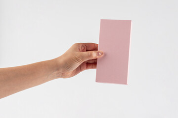 Obraz premium A small pink gift wrapping box and hand against a white background.