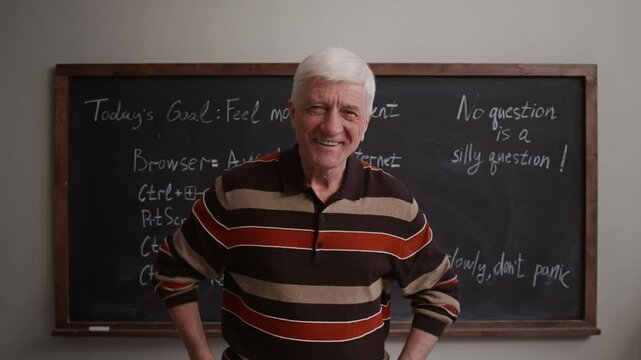 Medium portrait of confident and rejoiced Caucasian senior male student posing for camera while standing against chalkboard in modern classroom setting