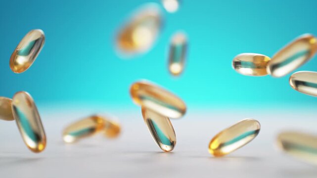 Yellow Fish Oil Softgel Capsules Fall Onto A Table And Bounce In Slow Motion and Macro, Blue Background