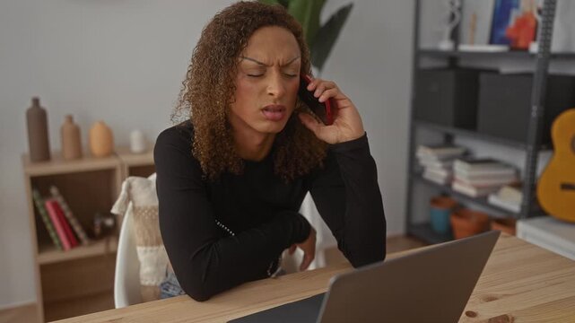 Transgender woman holds smartphone to ear with frown at wooden desk in building; work stress and tension.