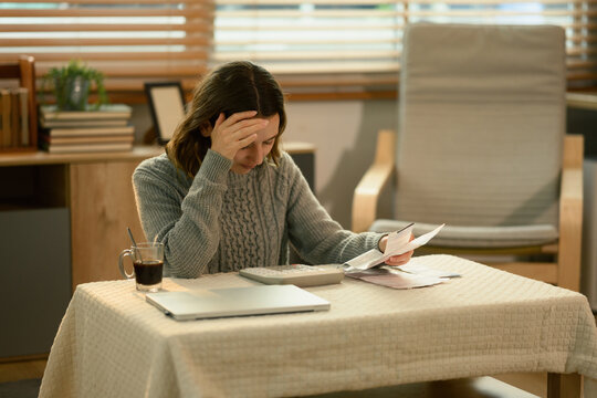 White woman overwhelmed by financial pressure, analyzing documents and thinking about ways to reduce expenses