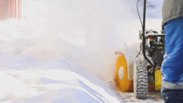 Removing snow with portable blower machine during winter, worker with gas snow blower removal in the streets after snowfall, clearing residential sidewalk driveway with snow sweeper, snowplow machine