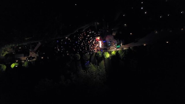 Aerial night shot of a traditional Indian wedding baraat with decorated car, dancers, and festive lights in india