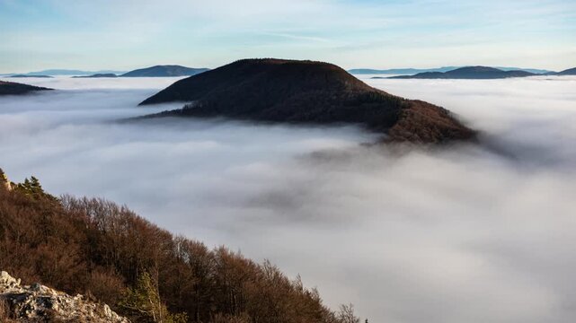 Sunset with clouds, sun rays, and misty valleys witn forest, mountain and peak nature landscape.