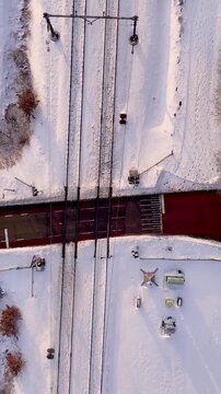 Car crossing railroad tracks in snowy winter landscape aerial view