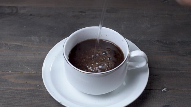 Hot water is slowly poured to brew coffee, creating a soft hiss, gentle splash, and steady flow echoing inside a white cup