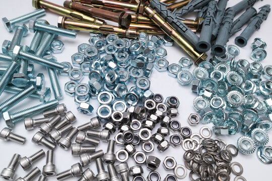 Assorted industrial fasteners including bolts, nuts, screws, and sleeve anchors on white.