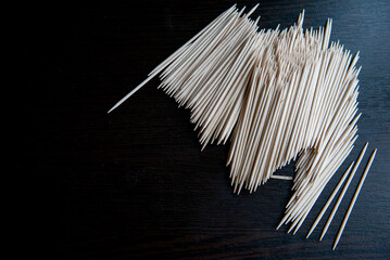Wooden toothpicks scattered on dark textured surface