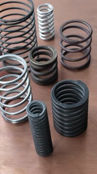 Metal springs of varying diameters and materials arranged on a copper surface.