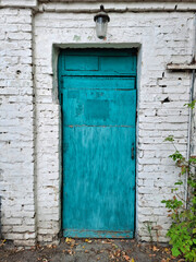 Old blue closed door. Autumn leaves are scattered at the entrance