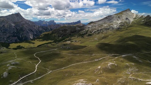 Drone video orbit over Rifugio Sennes on Plateau, rotation reveals surrounding Dolomites peaks ridges and alpine meadows under cumulus clouds in South Tyrol in Italy