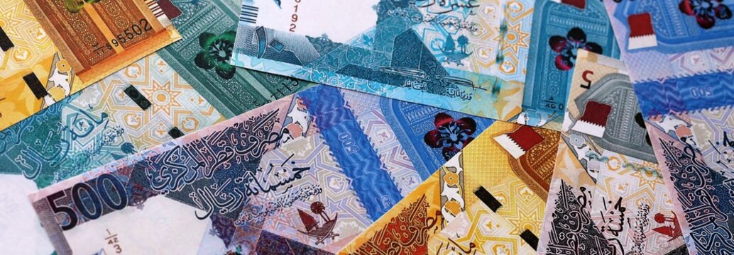 Qatari riyal money bills pile on table. Qatar banknotes of QAR currency close up.