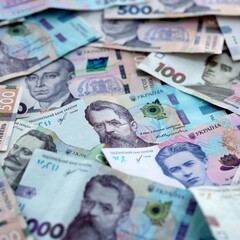 Obraz premium Ukrainian hryvnia money bills pile on table. Ukraine banknotes of UAH currency close up.