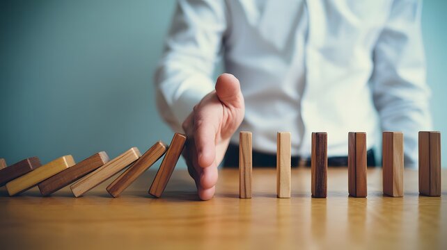 Strategic hand intervention halts domino chain reaction, symbolizing effective risk management, crisis prevention, and business control to avert negative consequences