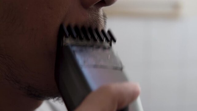 Close-up mustache shave with a portable trimmer, creating a soft electric buzz, steady hum, and short raspy hair-cut ticks near skin