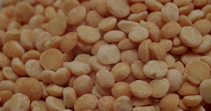 Yellow split peas rotating in a white bowl. Macro view of raw, dry yellow split peas rotating in slow motion, showcasing their texture and warm color as a background for healthy cooking concepts