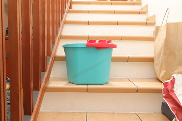 Blue bucket and paper bags on indoor stairs