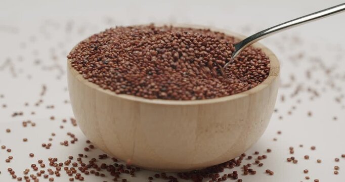 Red organic quinoa seeds rotating in slow motion, providing a detailed texture view of the healthy uncooked grain. The macro shot highlights the superfood's quality for wholesome nutrition.