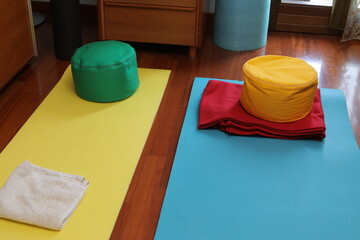Colorful yoga mats and meditation cushions on wooden floor