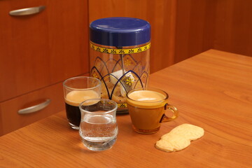 Espresso coffee, water, sugar and cookie on table