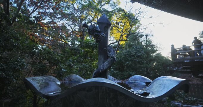 Medium silhouette shot of dragon statue fountain outside of ancient Japanese structure