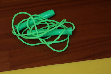 Green jump rope resting on wooden floor ready for fitness training