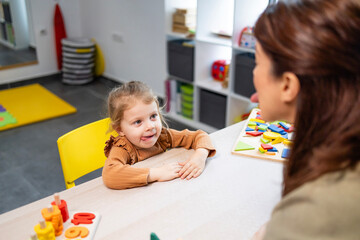 Speech therapist working with a young child on articulation and oral motor exercises during a...