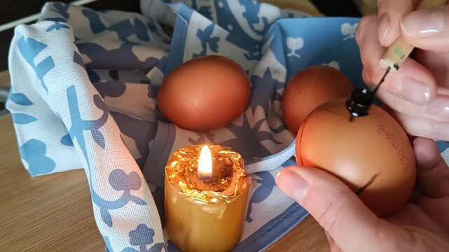 Traditional Pysanka Easter Egg Decorating with Wax Stylus Heated Over Candle Flame Close Up