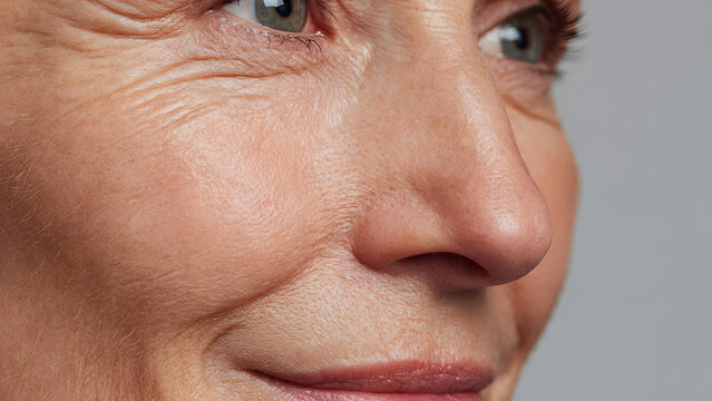 Close-up of mature woman&rsquo;s face with natural wrinkles and healthy glowing skin, age positive skincare and beauty concept