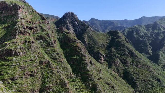 Aerial tracking shot over the rugged Anaga Massif peaks and the prehistoric barrancos of Punta del Hidalgo