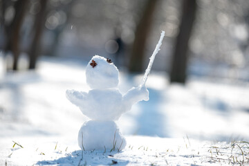 funny snowman holding an icicle like a conductor&rsquo;s baton, as if conducting the arrival of spring. small handmade snow figure standing in sunlight on sparkling snow. playful seasonal concept.transition