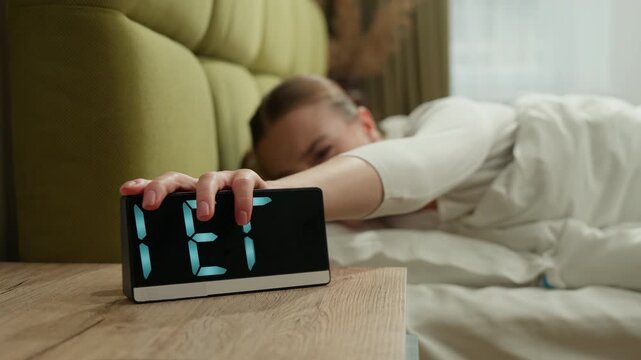 Caucasian woman awaking in bed in morning with alarm clock angry fatigued girl female wake up at home new day upset sleep disorder in bedroom loud sound ringing lady beating off device health trouble