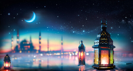 Ramadan Kareem - Arabic Lanterns With Crescent Moon -  Eid Ul Fitr - Defocused Mosque At Night With Abstract Glittering In The Air And Bokeh Lights