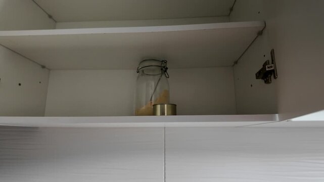 Woman opening almost empty pantry, food shortage and inflation concept