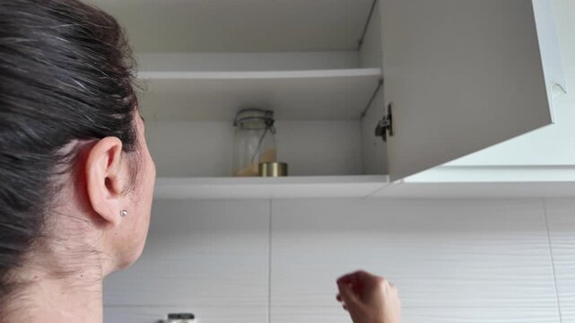 Woman opening almost empty pantry, food shortage and inflation concept