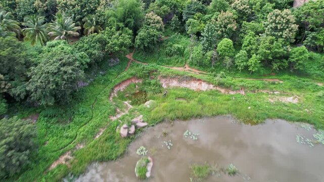 Tracking drone view of an adventurous boy zip-lining amidst the lush green hills of Ramanagara