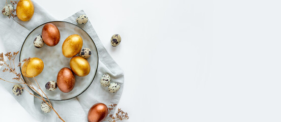 Golden and bronze Easter eggs in a grey plate on a linen napkin on a white background