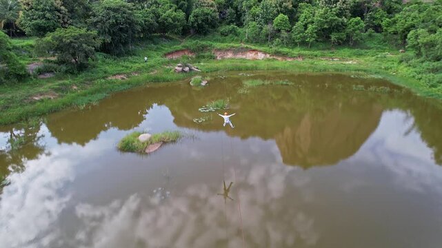Tracking drone view of an adventurous boy zip-lining amidst the lush green hills of Ramanagara