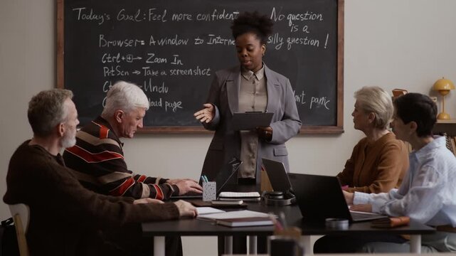 Black female teacher engaging senior students in interactive discussion during lesson in modern diverse classroom learning environment