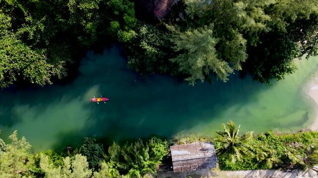 Kayakers glide effortlessly over the tranquil waters of Koh Chang, Thailand, surrounded by vibrant foliage and serene landscapes. A perfect escape into nature unfolds here.