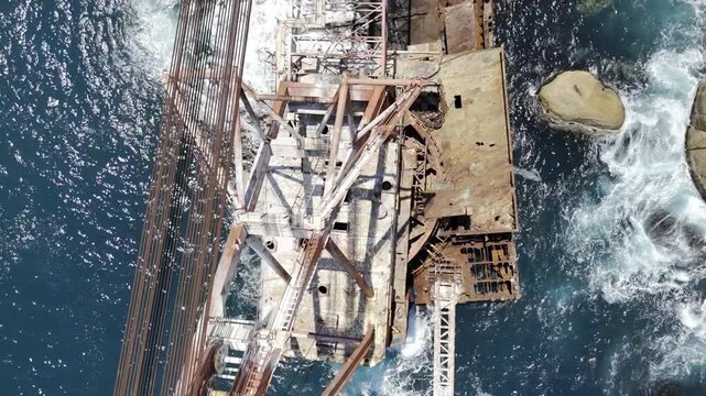 Drone flies north with bird's eye view of Bos 400 shipwreck in Hout Bay on a sunny morning in Cape Town, South Africa