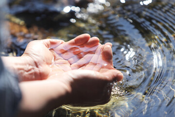 The clear, clean water of a pristine stream, the precious water of life held in your hands, World Water Day background 
