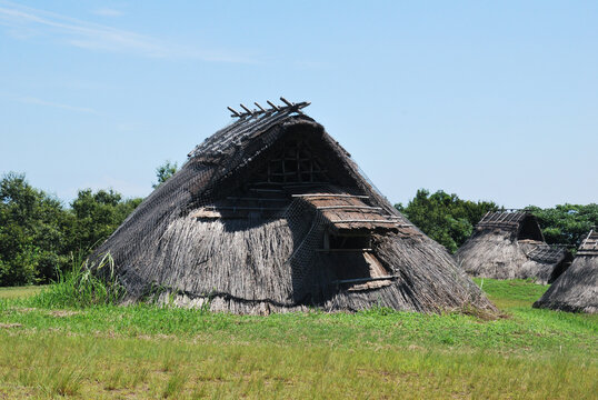 青空の下の草原に復元された古代の竪穴住居