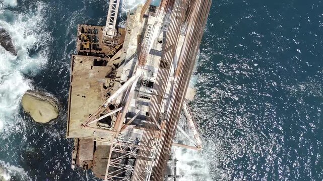 Drone flies south with camera down over Bos 400 shipwreck on a sunny morning in Cape Town, South Africa