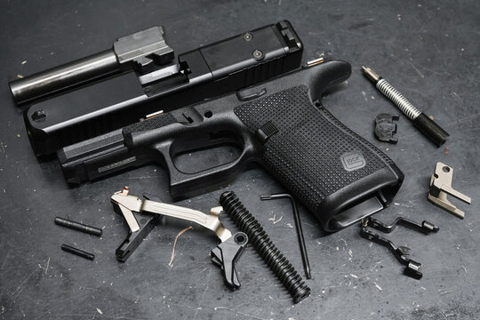 TALLINN, ESTONIA - FEBRUARY 20, 2026: Disassembled Glock 19 Gen 6 semi-automatic pistol with internal components, slide, and barrel on workbench.