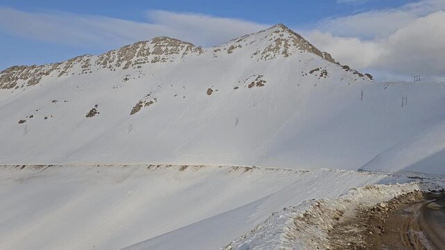 Snowy mountain landscape featuring a winding mountain road, high snowbanks, and towering peaks under bright winter light in a remote alpine region.  
📍Hawraman Takht, Kurdistan 