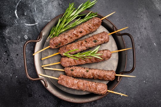 Grilled minced beef and lamb kebabs skewers with fresh spices, arabic kofta kofte kebab. black background. top view