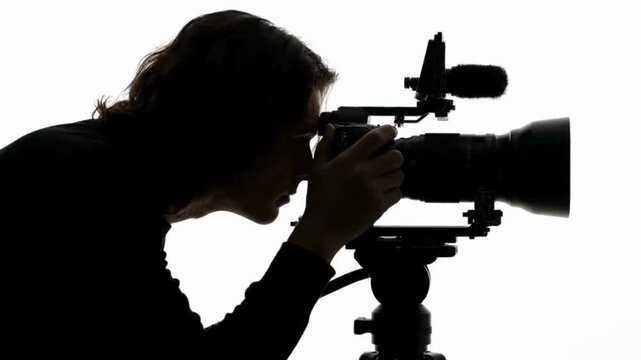 Professional videographer adjusting cinema camera on tripod studio setup