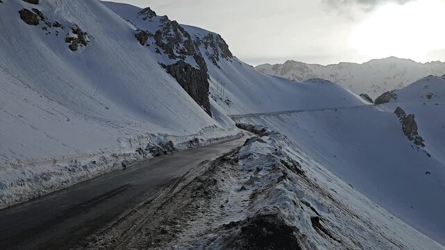 Mountain pass road bordered by a tall snowbank on one side, set beneath a cloudy winter sky and surrounded by rugged, icy terrain.
📍Hawraman Takht, Kurdistan 